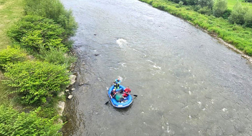 Rzeka, na niej niebieski ponton z ludźmi w środku