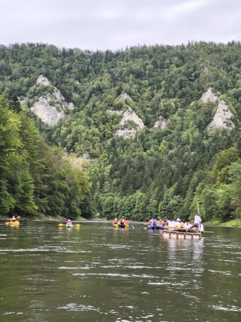 Wapienne skały porośnięte lasem, flisackie tratwy i kajaki na Dunajcu