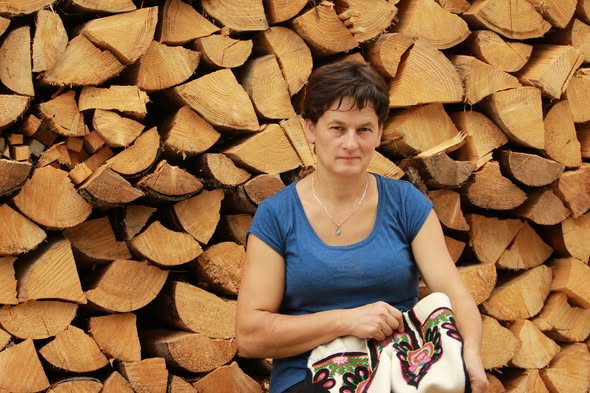 Harciarka w niebieskiej blużce siedzi na tle porąbanego drzea