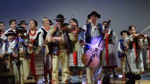 Zdjęcie grupowe: Muzycy z zespołów regionalnych "Pienińskie Wiyrchy" i "Małe Pieniny" w tradycyjnych strojach góralskich grają na instrumentach (skrzypce, basy) podczas koncertu kolęd w Centrum Kultury i Promocji w Krościenku nad Dunajcem.