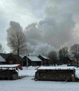 Zima, dym pożaru na tle nieba, zabudowania wiejskie