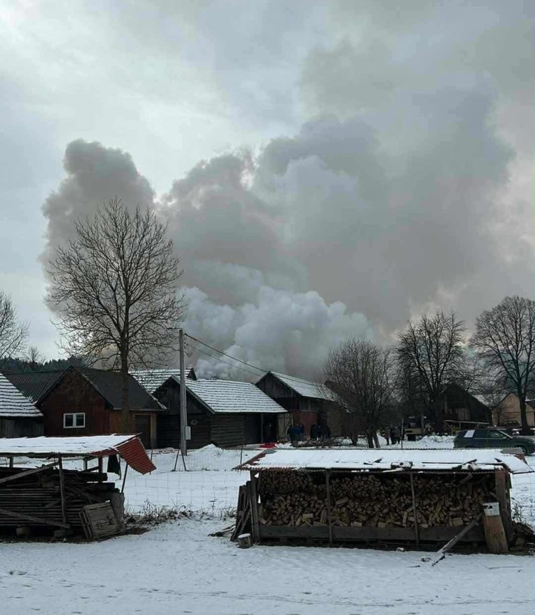 Zima, dym pożaru na tle nieba, zabudowania wiejskie