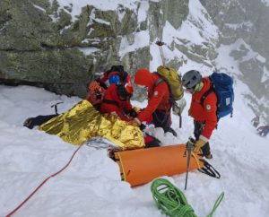 Ratownicy TOPR transportują ranną osobę w noszach pod Rysami