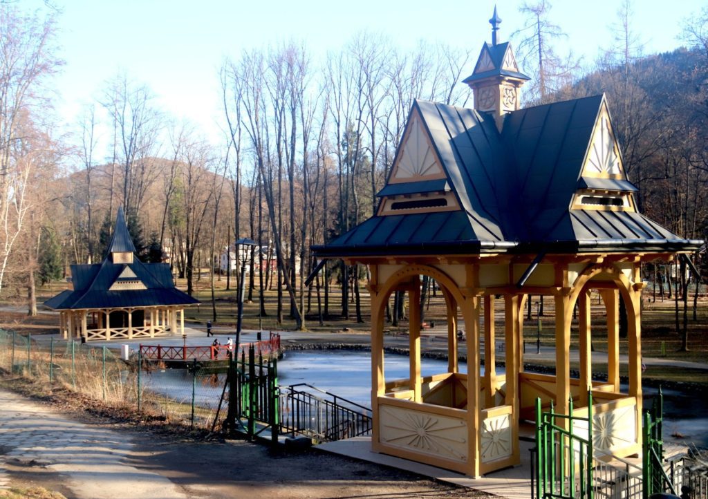 Odnowiona zabytkowa altana widokowa w Park Dolny w Szczawnicy po renowacji – drewniana konstrukcja z ozdobnymi detalami i kamiennymi schodami w otoczeniu zieleni.